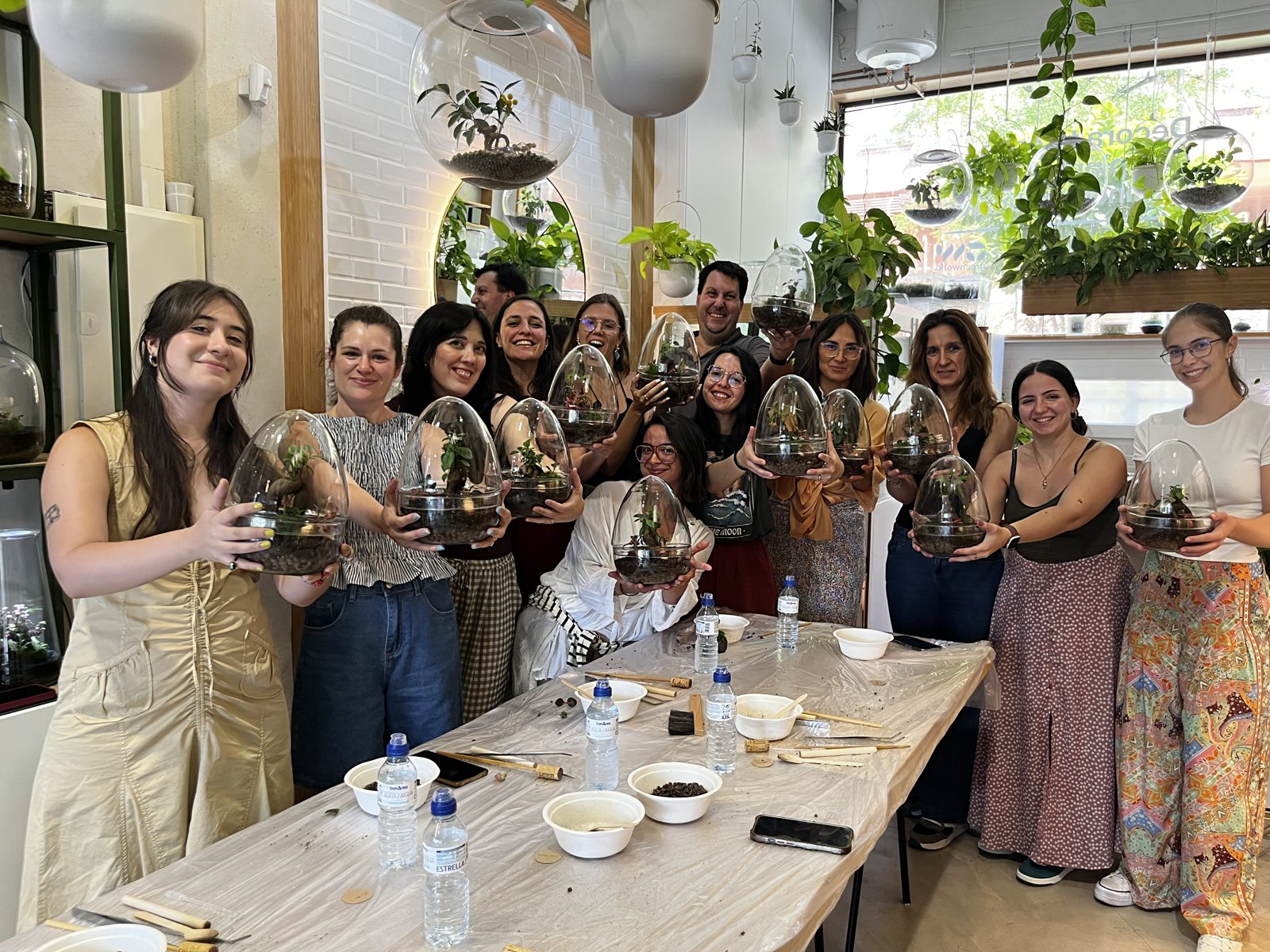 Equipo de Integral Media Projects sonriendo con terrarios durante una actividad de grupo